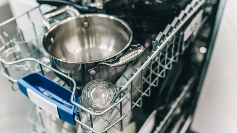 A small dishwasher is open and filled with dishes