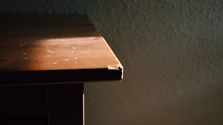 A wood table has a chipped corner