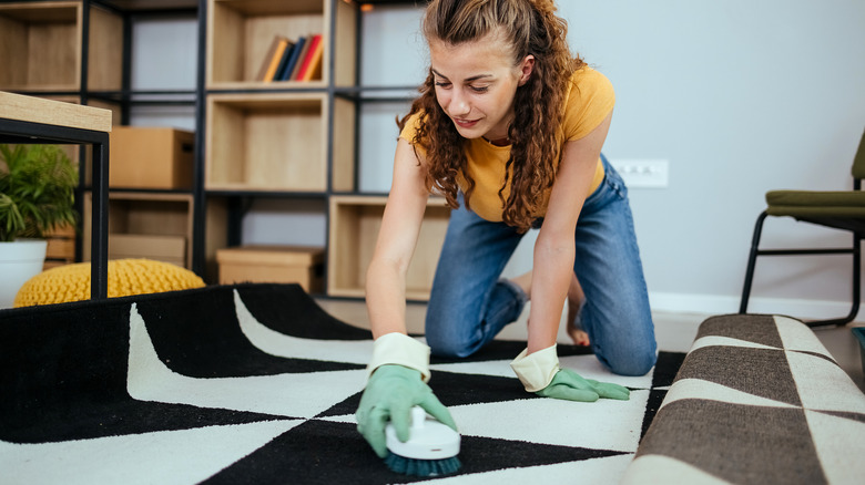 A woman spot cleans a wool rug