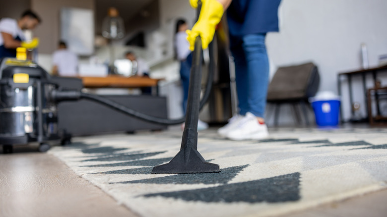 A person vacuums a wool rug