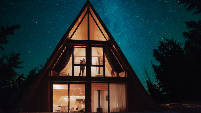 brightly lit a-frame house from outside at night