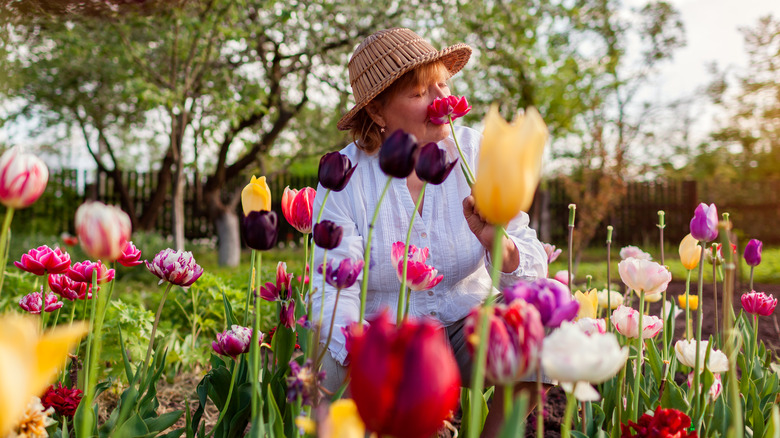 A woman smelling flowers in her yard