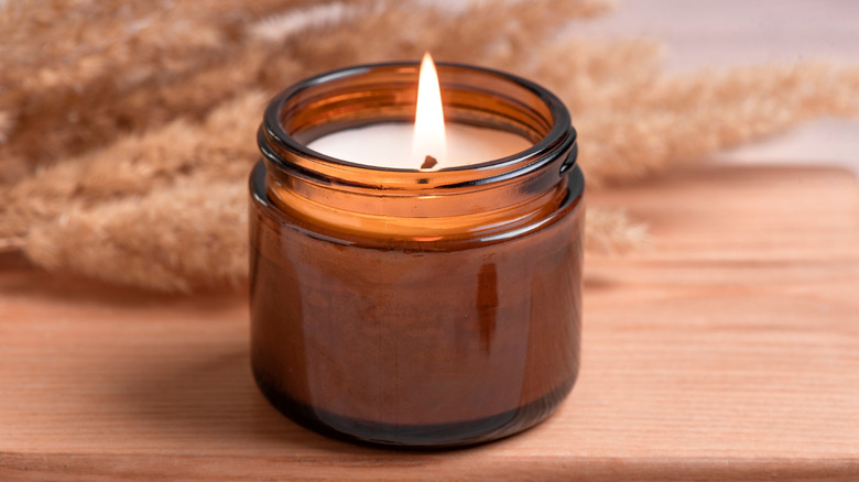 Small candle burning in amber jar