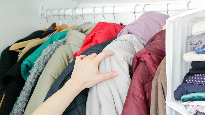 Person pulling coat out of closet