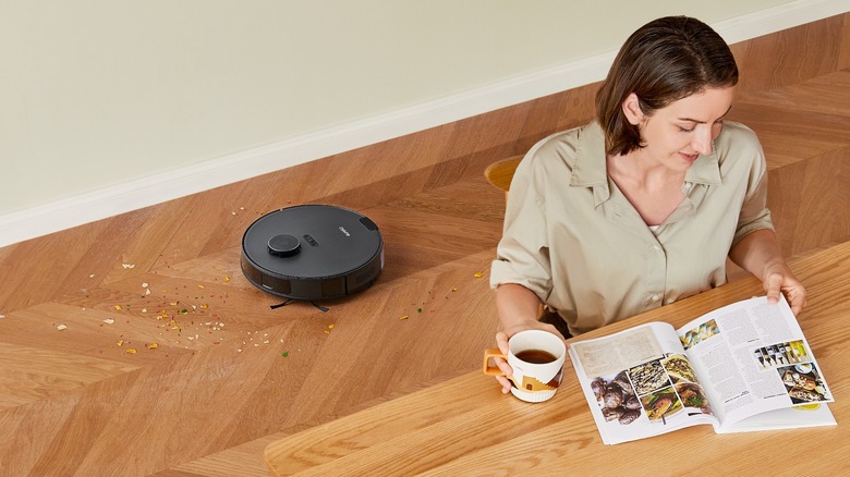 Vacuum behind woman reading magazine