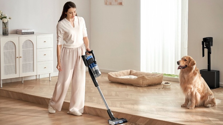 eureka vacuum cleaner being used by woman beside golden retriever