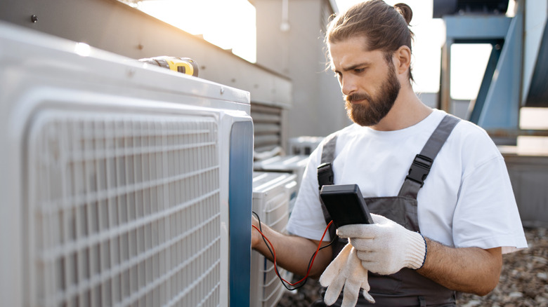 Man testing an AC unit with a digital multimeter