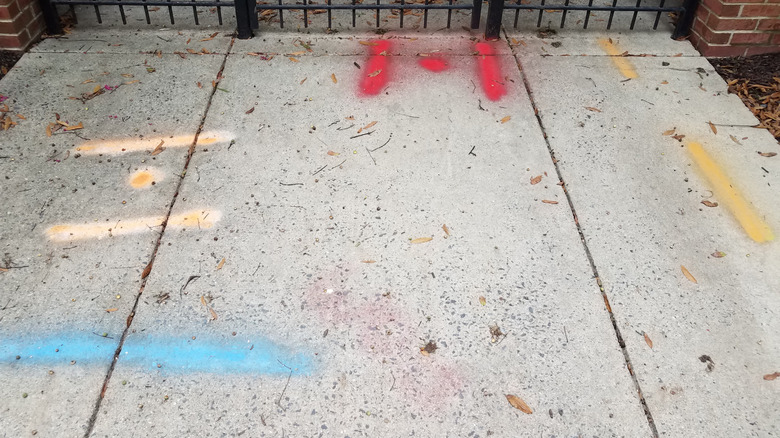 Faded blue, yellow, and red spray paint on a sidewalk