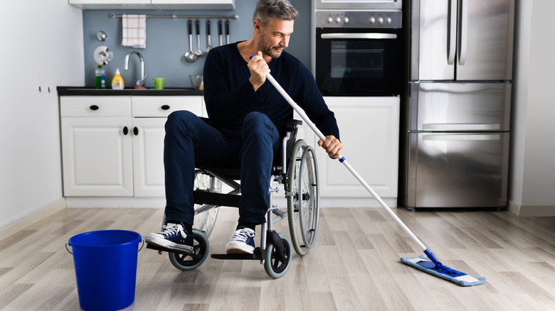 Man in wheelchair mopping floor