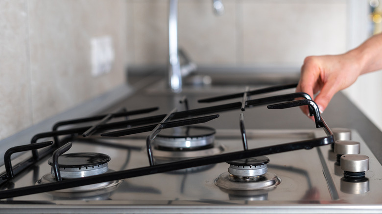 woman's hand lifting clean gas stovetop