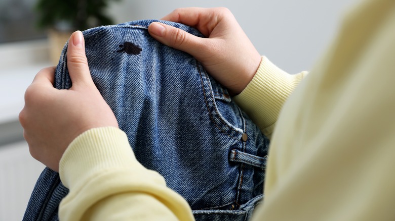 woman examining ink stain on jeans