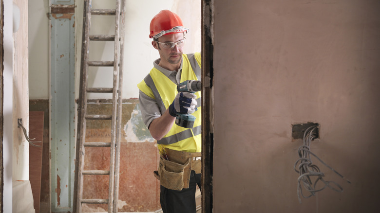 Construction worker using a cordless drill/driver on a door frame