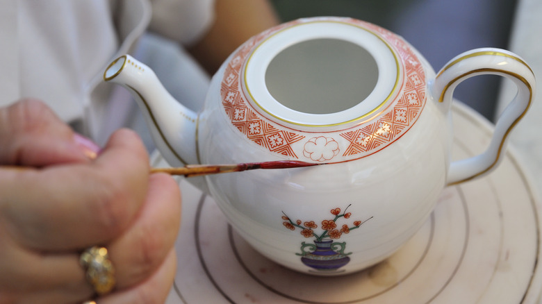 artist hand painting teapot