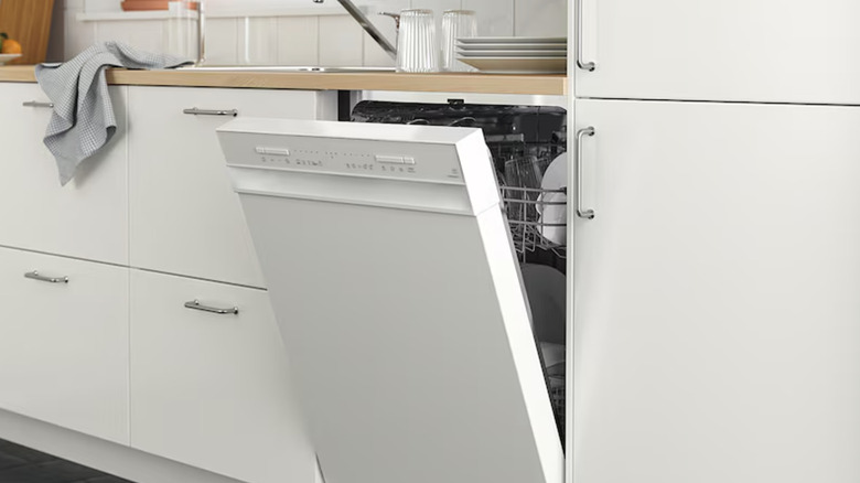 Open white IKEA dishwasher near white refrigerator