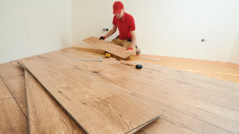 A man is installing vinyl plank flooring.