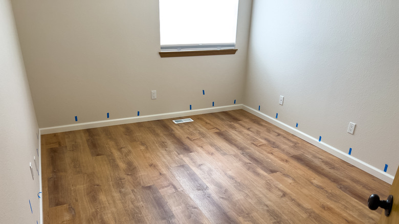 An empty room has vinyl plank flooring.