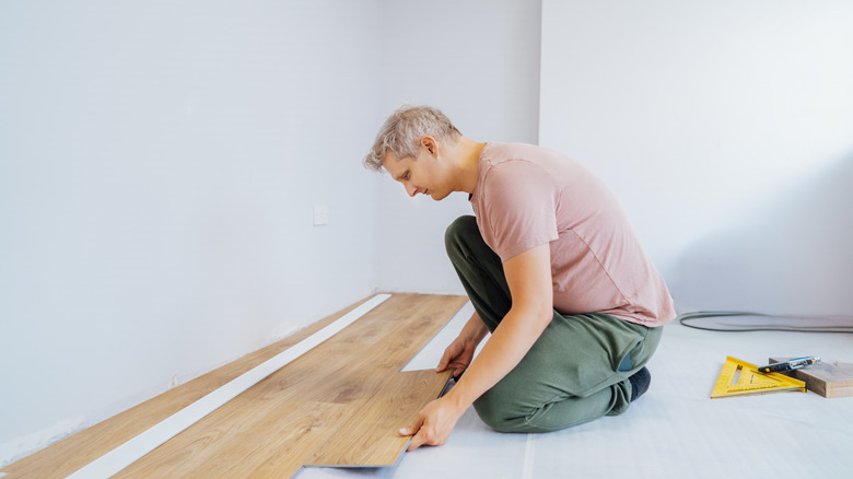 A man is installing vinyl plank flooring.