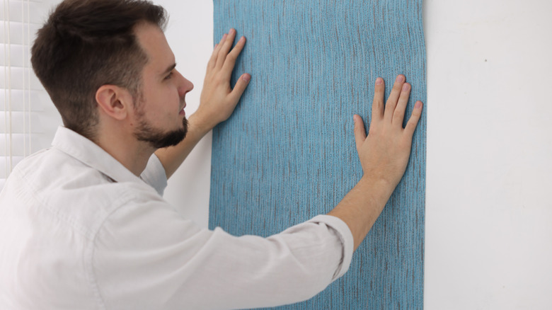 Man hanging textured wallpaper