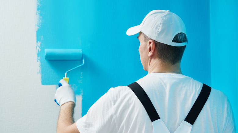 Worker painting drywall