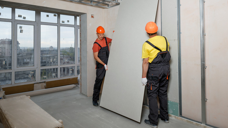 Construction workers hanging drywall