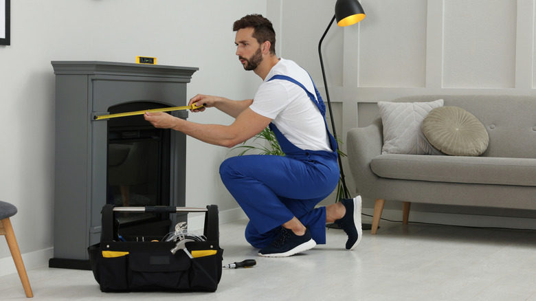 A handyman measuring a fireplace