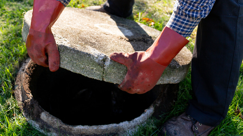 person opening the top of a septic tank