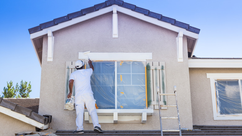 A person paints exteriors with Rhino Shield