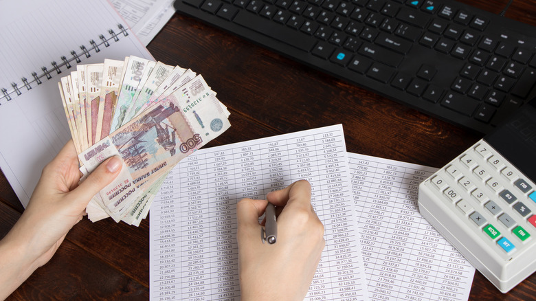 Person holding money at desk