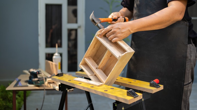 person hammering wooden diy project