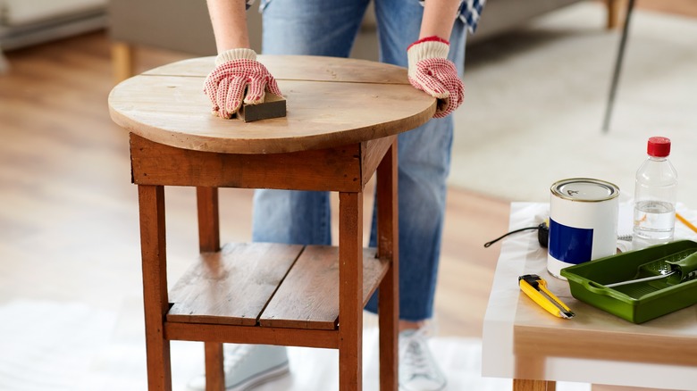 closeup of a small wooden table being sanded with a sandblock