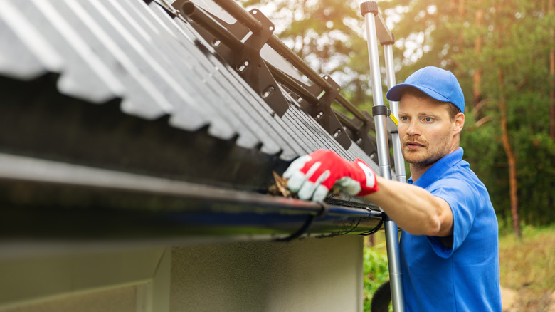 Person cleaning gutters