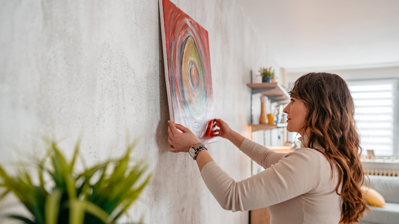 Person hanging art on wall