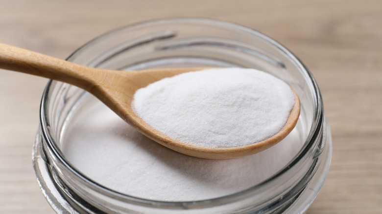 Baking soda in glass jar with wooden spoon