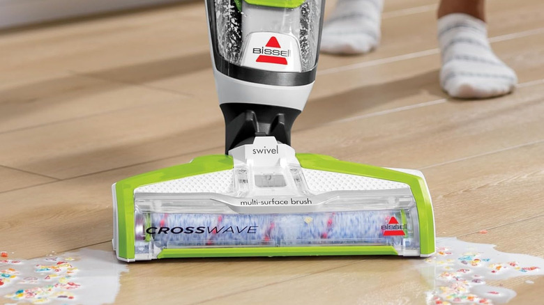 Person using Bissell CrossWave vacuum on hardwood floor