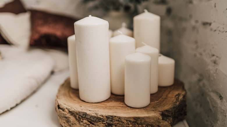 White candles of different sizes rest on a decorative tree stump slice