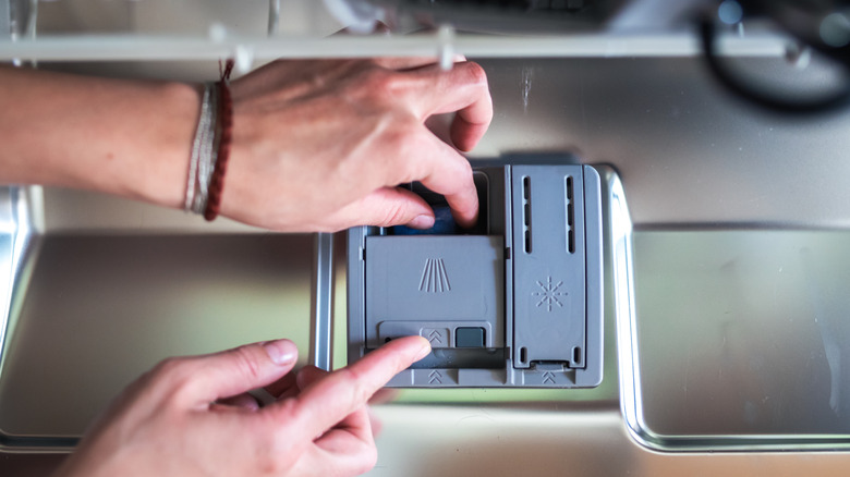 Woman's hand putting tablet in dishwasher