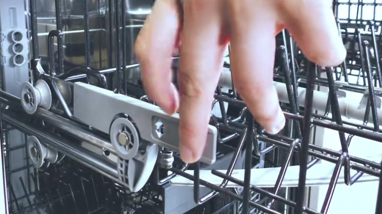 A person demonstrating the latch of a dishwasher rack testing 123