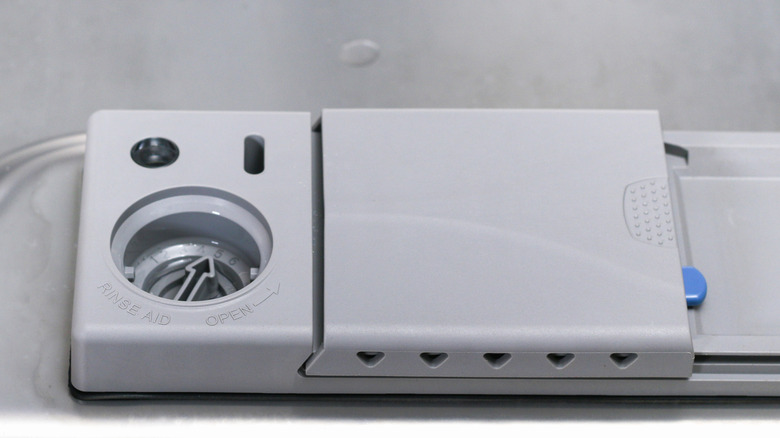 A dishwasher with an open rinse aid compartment