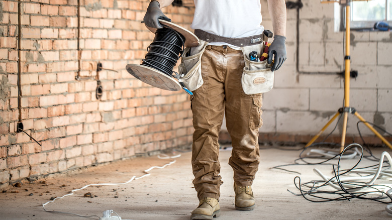 Man holding electric cable at construction site