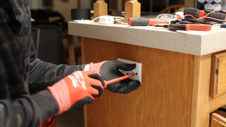 Screwing cover plate over new receptacle with USB-A and USB-C ports