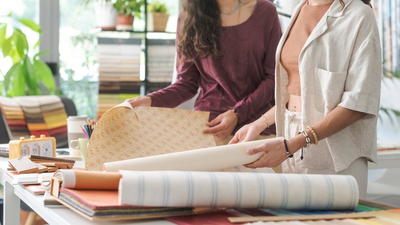 Two people handling wallpaper samples