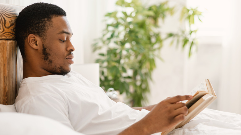 man reading a book in bed