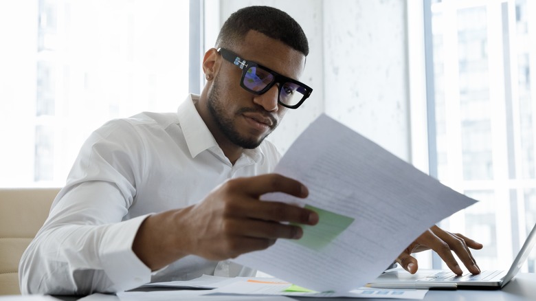 man with glasses analyzes paper