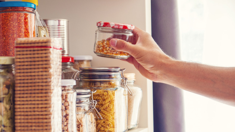 man stacking jars in cupboard