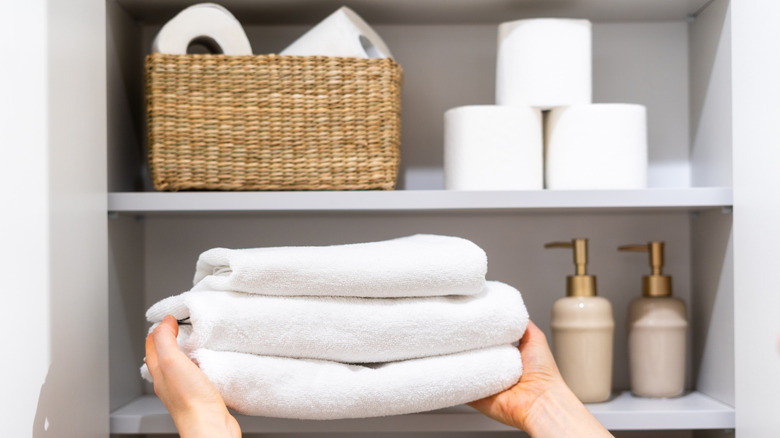 Hands placing towels on a linen closet shelf