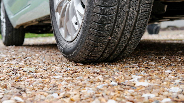 Close up of a car tire on a gravel driveway