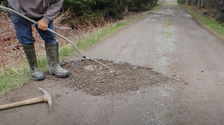 Person raking gravel that is added to a pothole