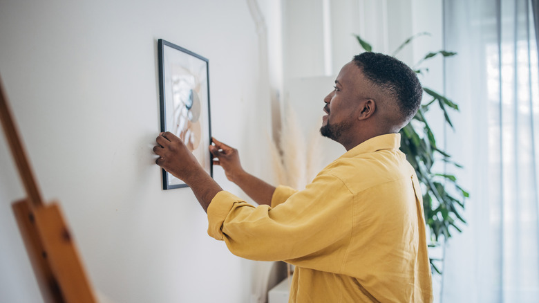 Person adding frame to wall