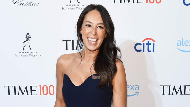 Joanna Gaines smiling in front of red carpet backdrop