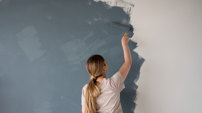 Woman painting wall with roller